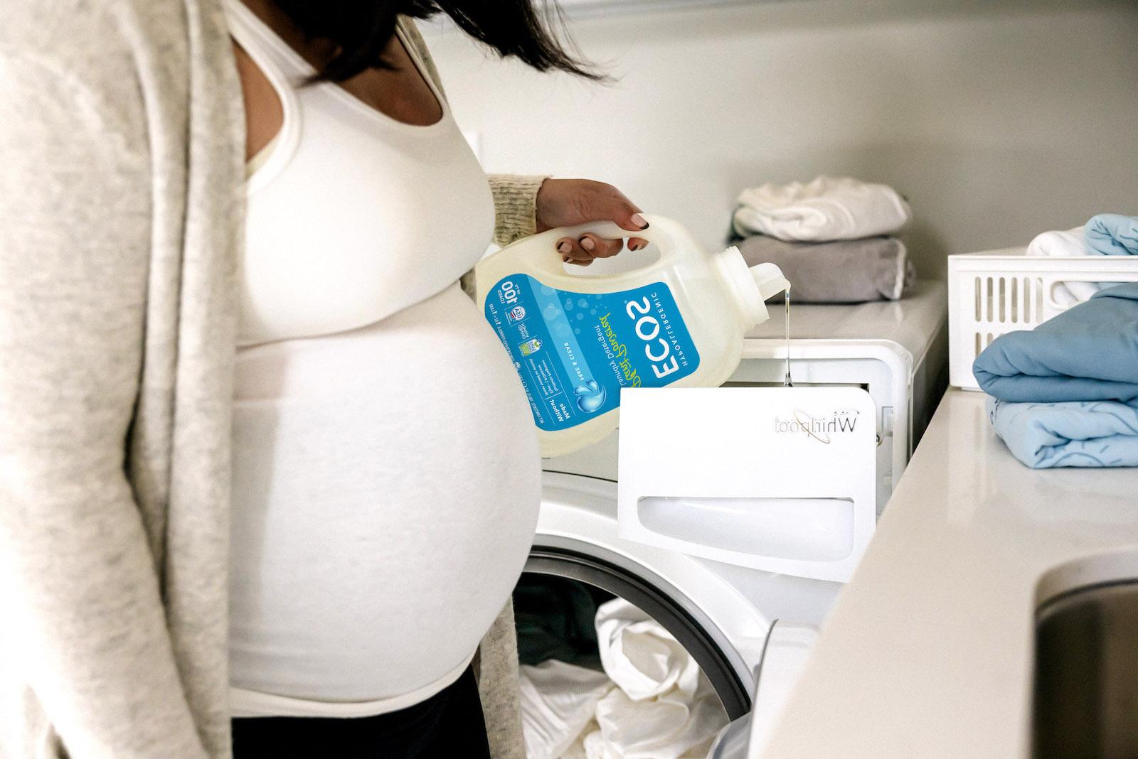 Pregnanat Woman Pouring Liquid Detergent into Washer