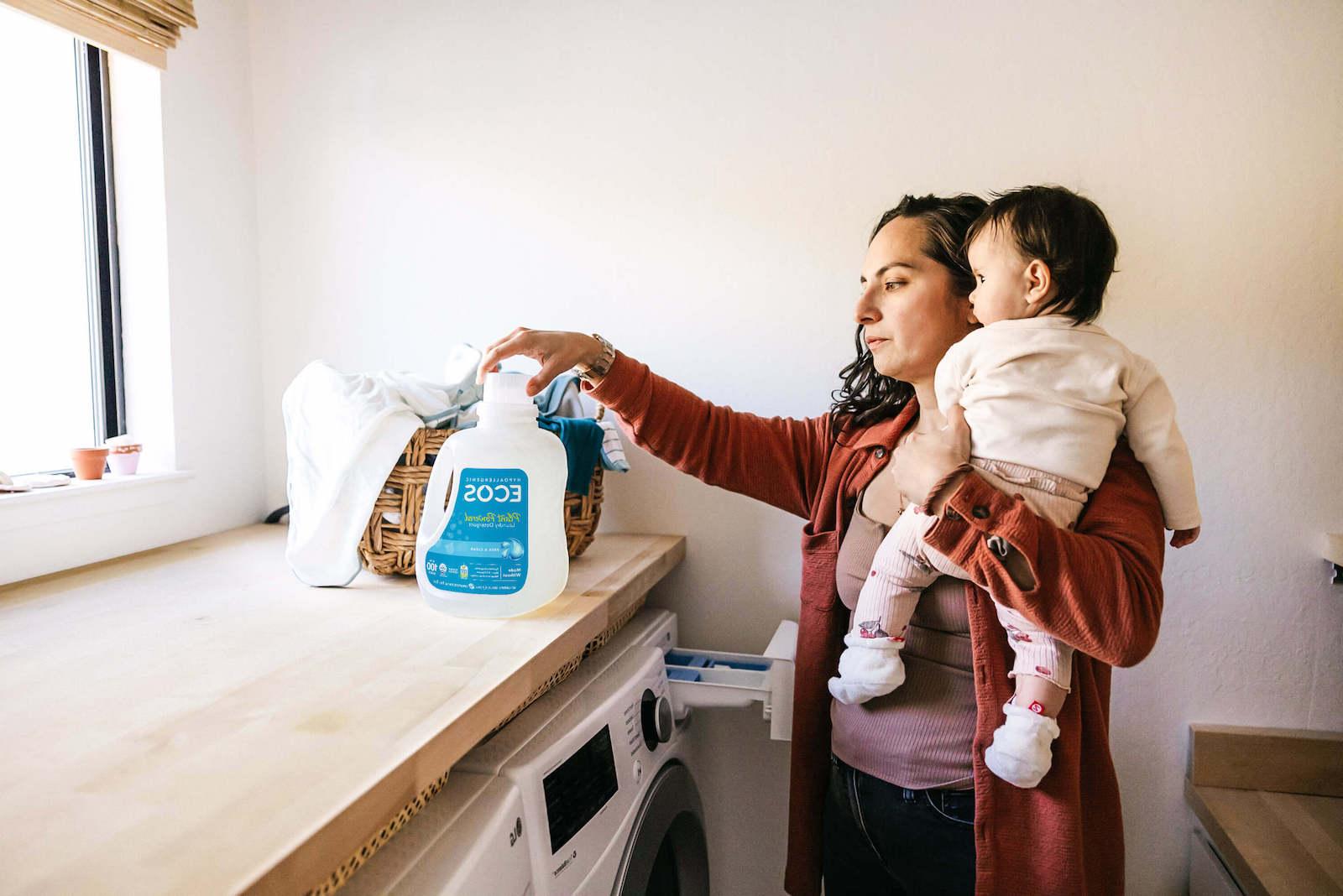 Mother Holding Baby While Doing Laundry