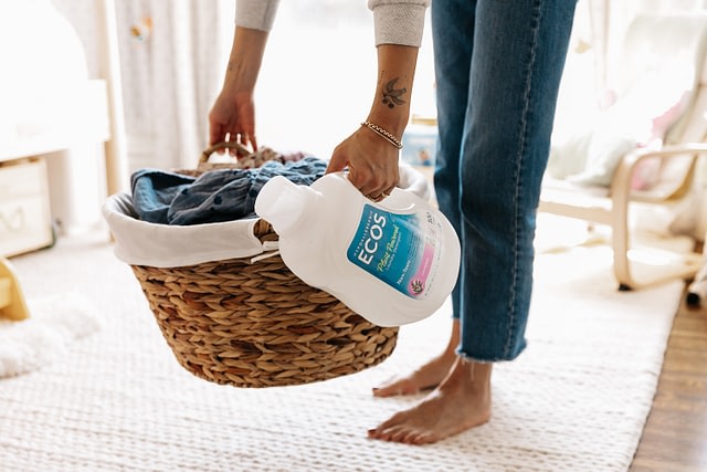 Woman Bending Over With Laundry Basket & Bottle Of Ecos Lavender Laundry Detergent